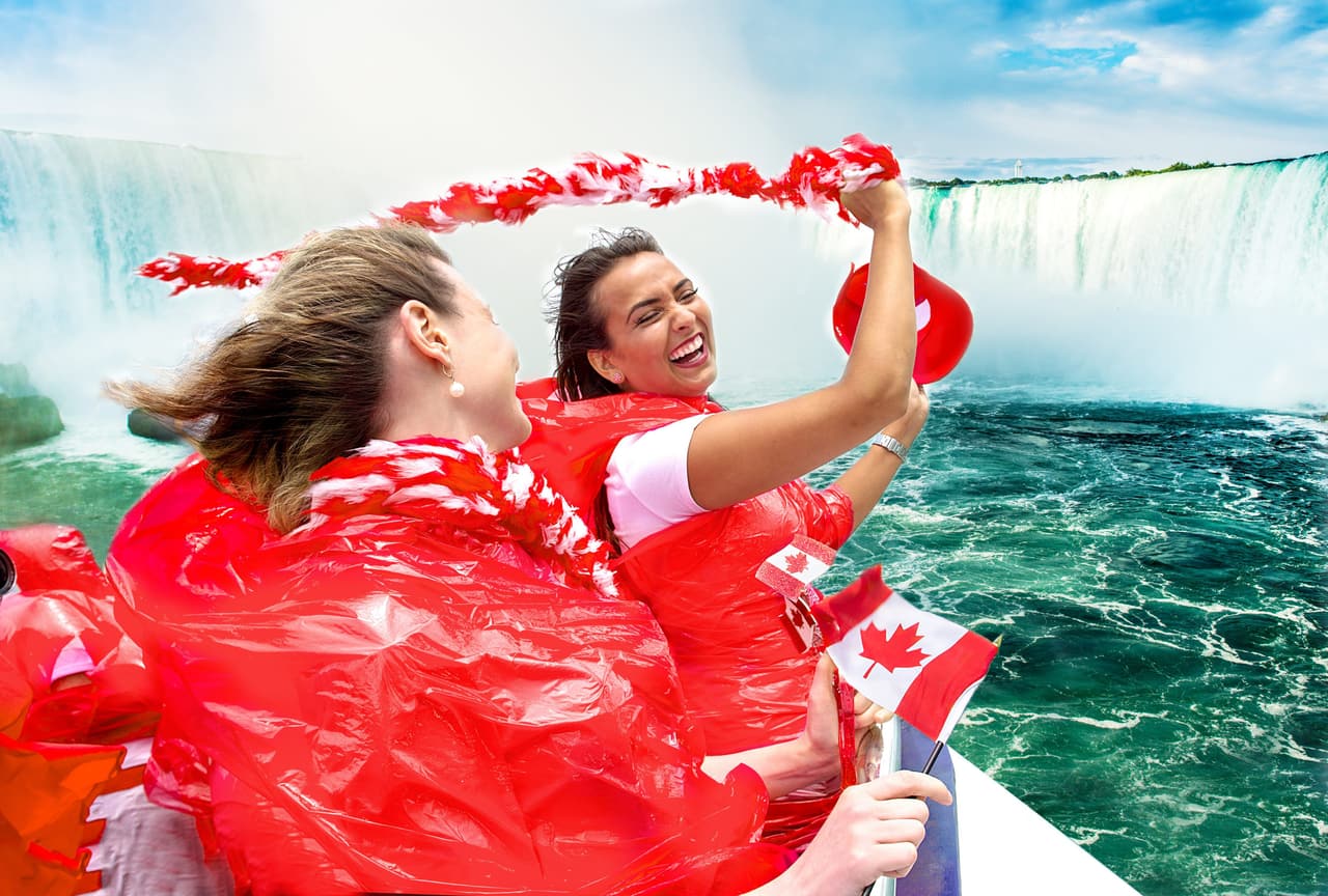 Two of our guests in red ponchos waving a Canadian flag on the Hornblower boat cruise