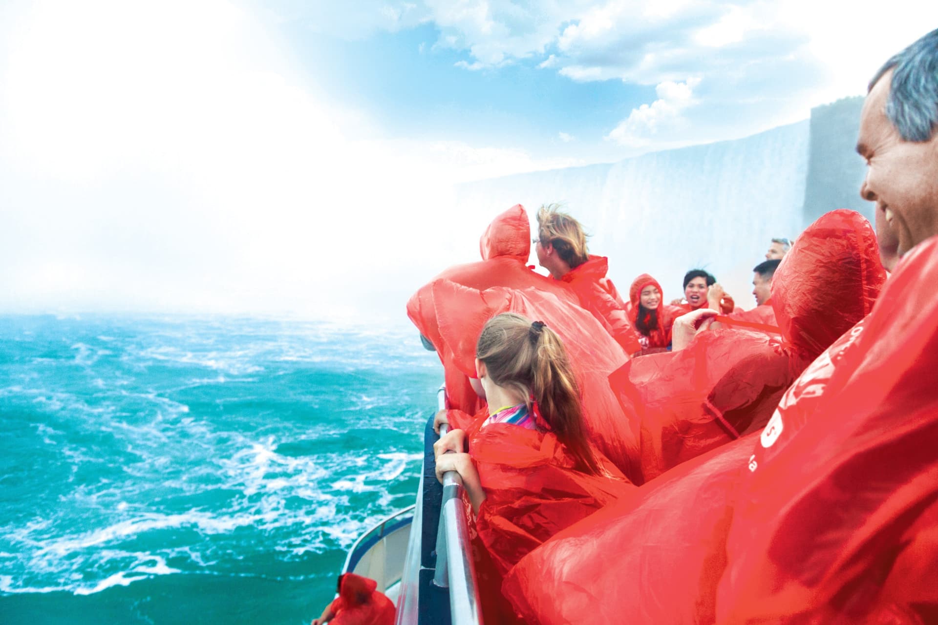 Guests in red ponchos on the boat at the foot of the Falls